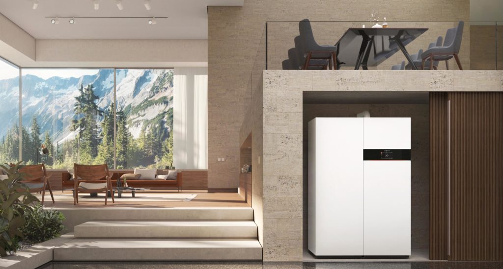 Intérieur moderne avec grandes baies vitrées sur des montagnes, salon avec fauteuils et canapé, et une buanderie équipée d’une grande machine blanche dans un renfoncement mural.