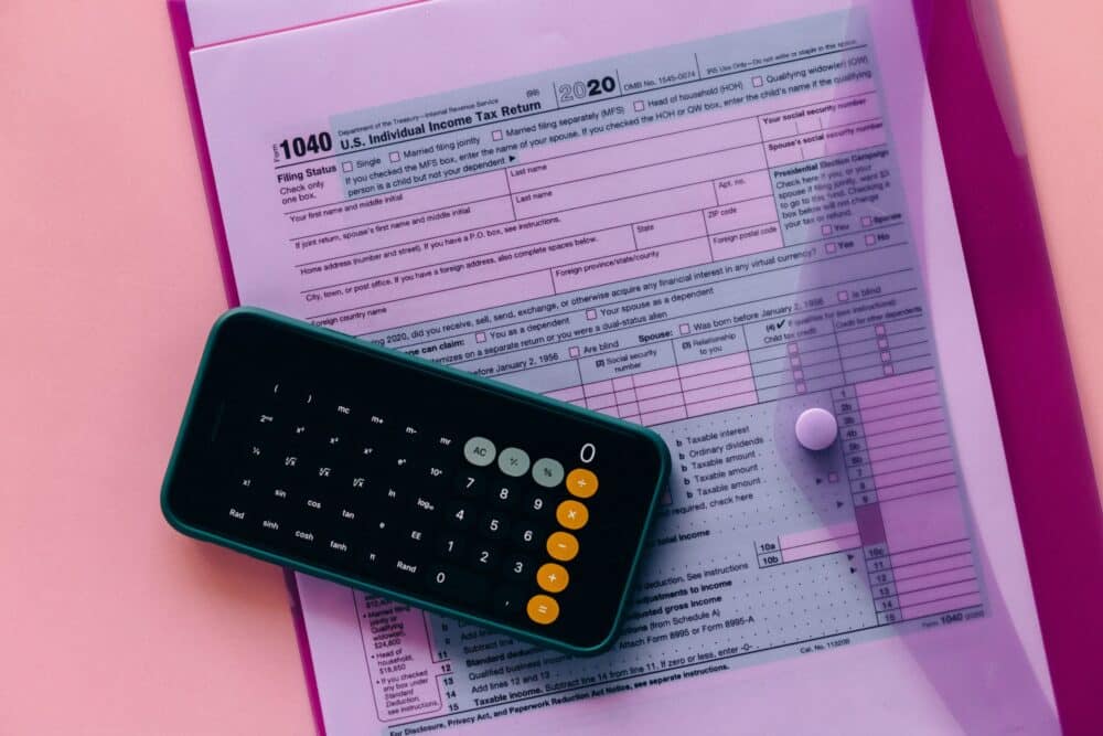 Formulaire fiscal américain U.S. Individual Income Tax Return (Form 1040) posé sur un bureau, avec une calculatrice en premier plan et la case “Filing Status” visible.