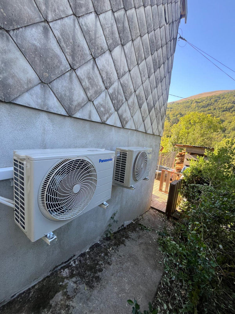 Deux unités extérieures de pompe à chaleur air-air Panasonic fixées sur la façade d'une maison à Saurat (09)